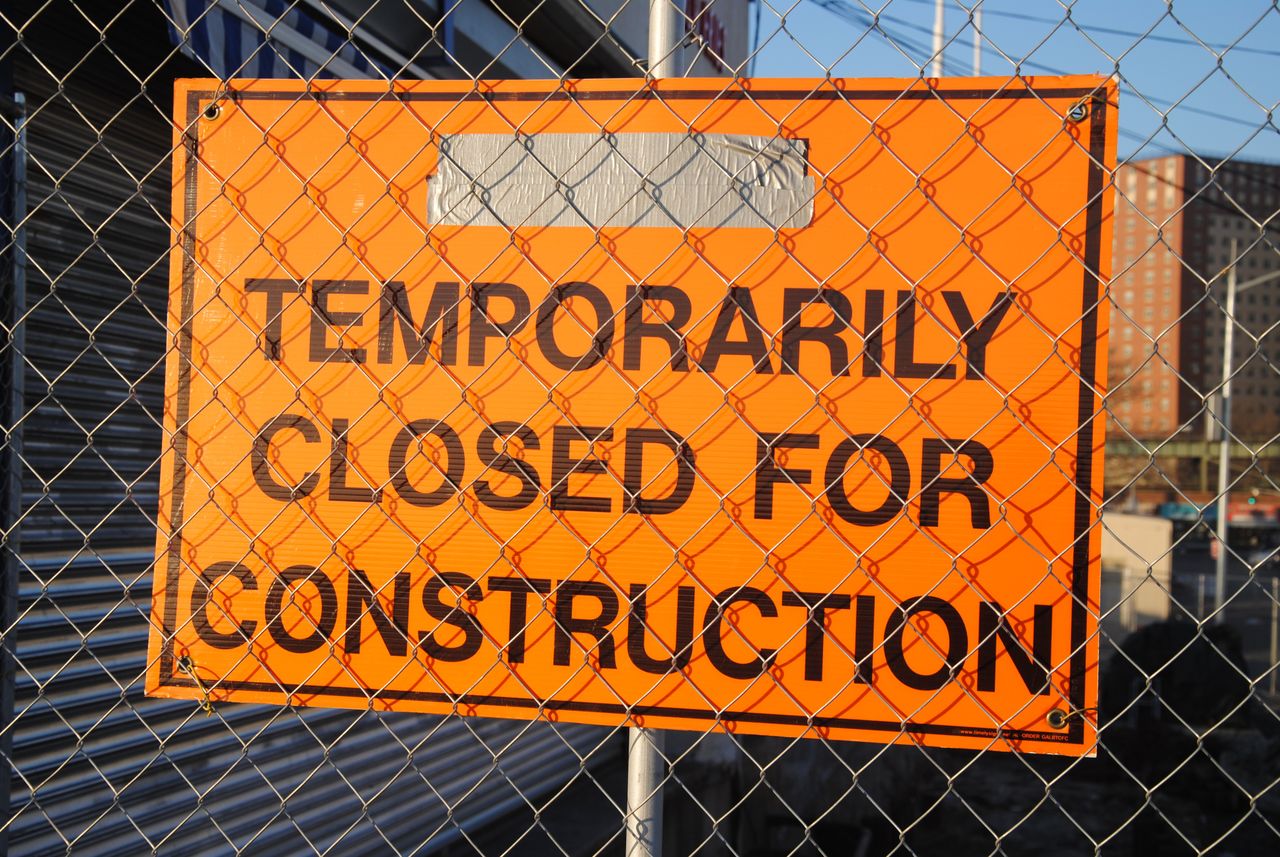 services-03 Orange sign behind fence reading 'Temporarily Closed for Construction' at site.