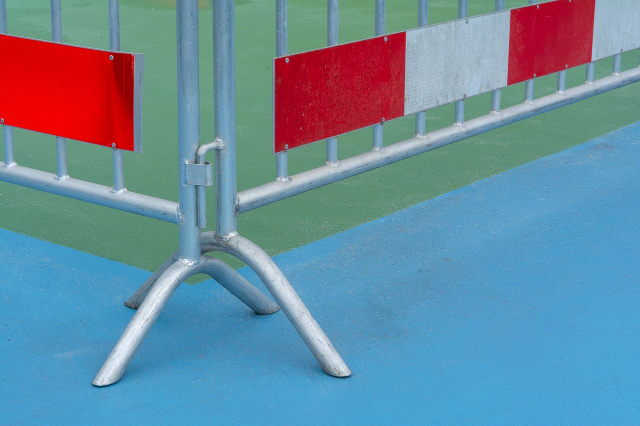 Crafting Captivating Headlines: Your awesome post title goes here Metal barrier with red caution sign on a vibrant blue and green background outdoors.