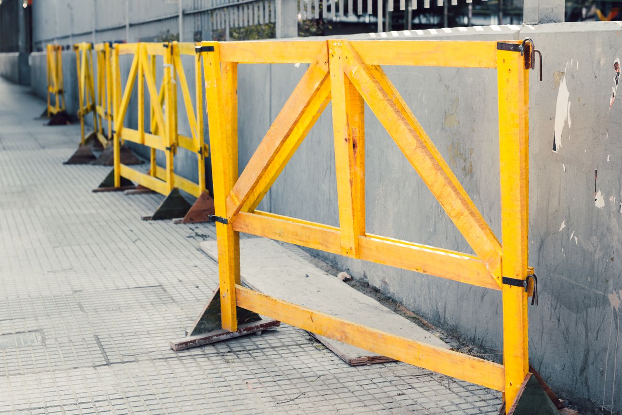 The Art of Drawing Readers In: Your attractive post title goes here Multiple yellow construction barriers line a sidewalk outdoors, creating a linear pattern.